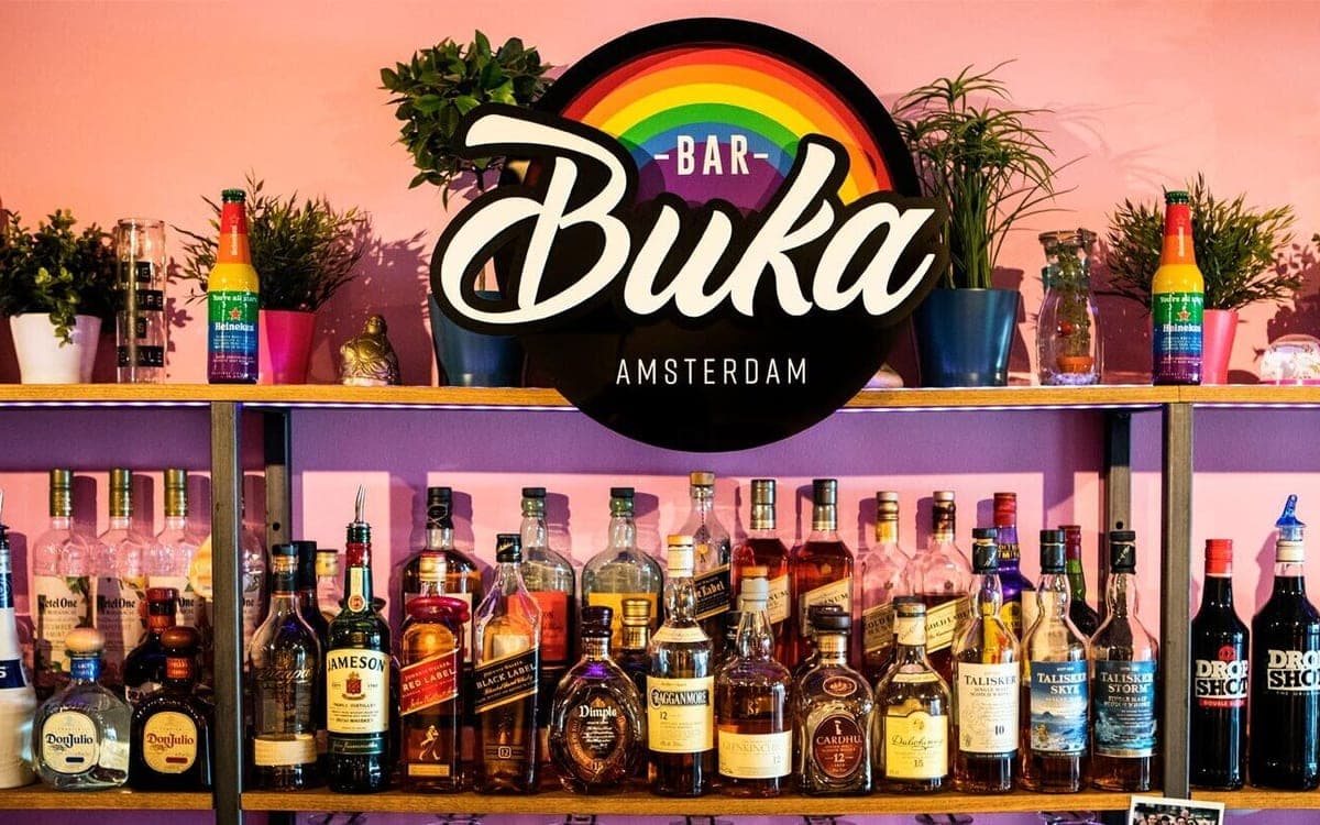 Interieur van Bar Buka in Amsterdam, met de bar en het regenboogbord.